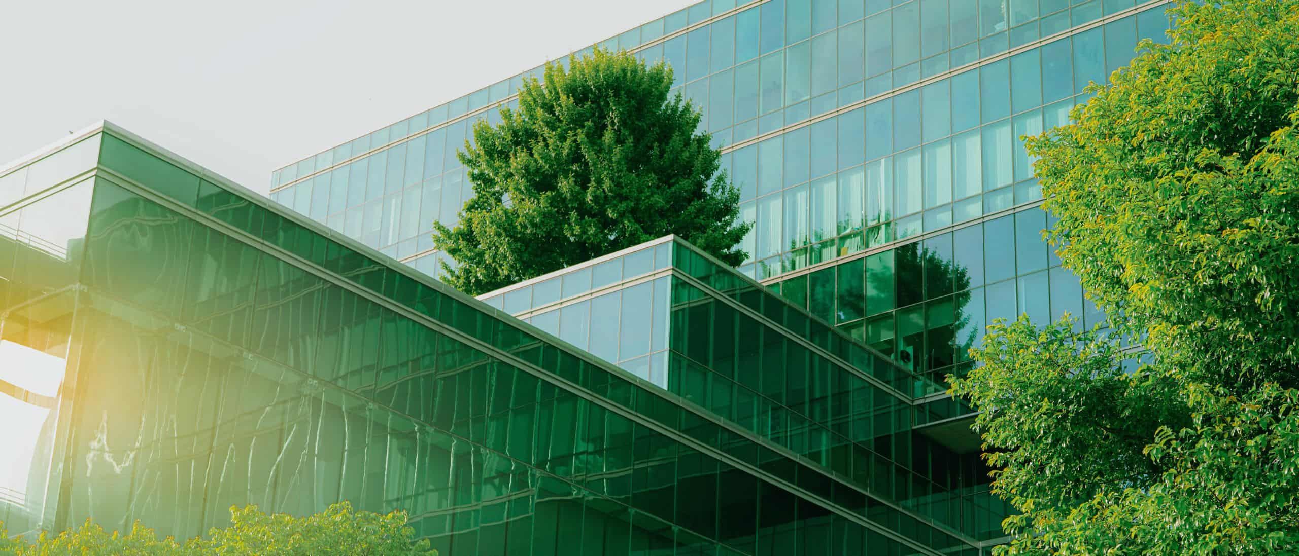 Nachhaltiges modernes Bürogebäude mit Glasfassade und begrünten Außentreppen in einer urbanen Umgebung.